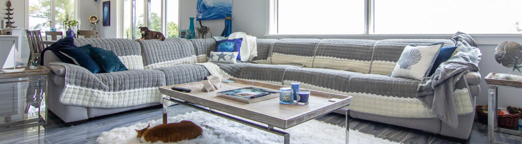 Elegant coastal-style living room featuring a large sectional sofa with blue and grey accents, showcasing custom home interior design ideas for Martin County homeowners