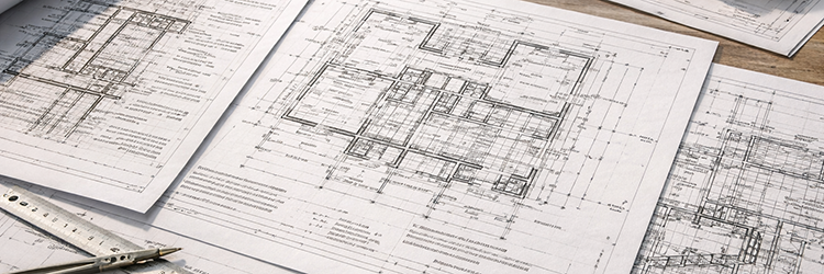 Close-up of custom home blueprints with drafting tools, showing the precision and planning behind the design phase of a Martin County construction project