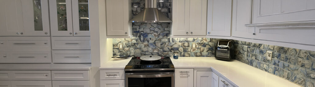 Modern farmhouse kitchen renovation featuring white shaker cabinets, stainless steel range hood, and an agate stone backsplash.