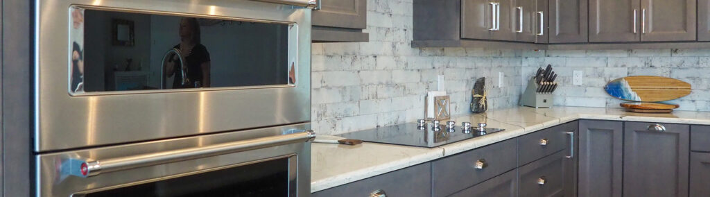 A finished kitchen renovation in Martin County showcasing custom gray cabinetry, quartz countertops, and a classic subway tile backsplash completed by Masterpiece Design/Build.