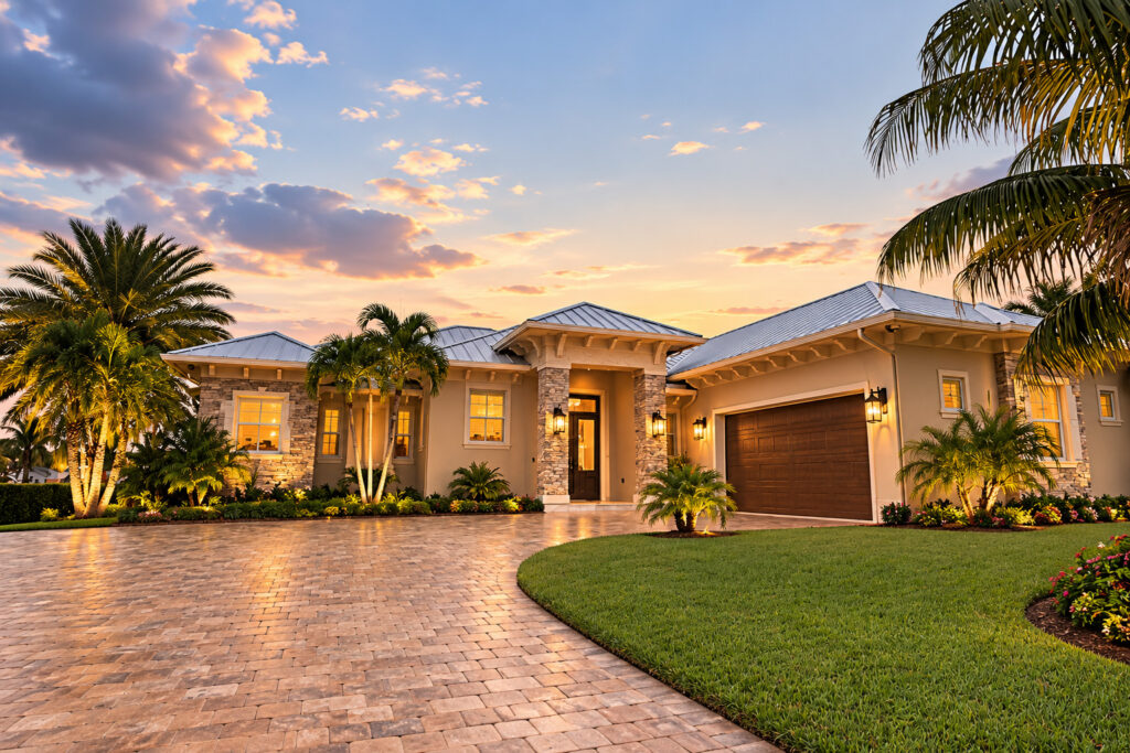 Private waterfront custom home at dusk with a standing-seam metal roof, built by Masterpiece Design/Build at Stuart Yacht & Country Club